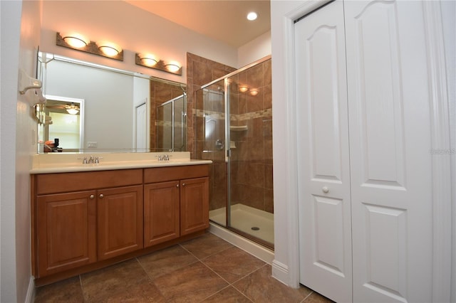 bathroom featuring double vanity, a stall shower, and a sink