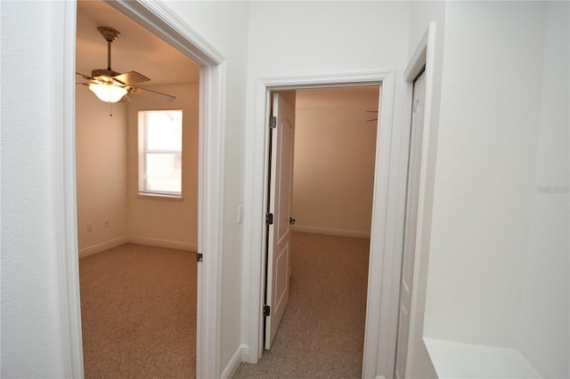 corridor with baseboards and light carpet