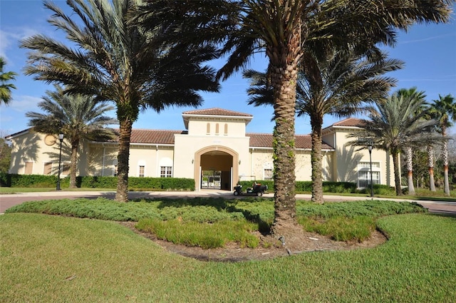 view of front of property with stucco siding, a tile roof, and a front lawn