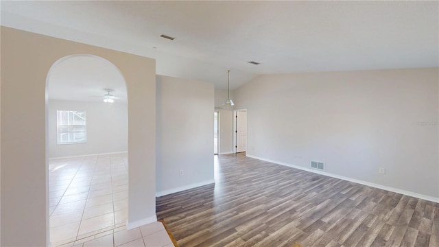 empty room featuring visible vents, lofted ceiling, ceiling fan, and wood finished floors