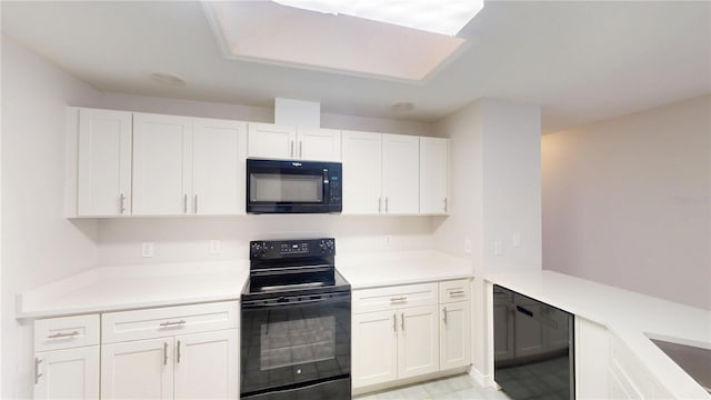 kitchen featuring white cabinetry, black appliances, light countertops, and a peninsula