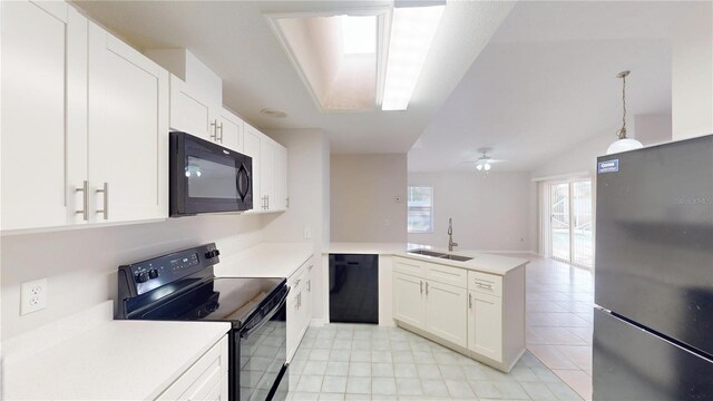 kitchen featuring a peninsula, black appliances, light countertops, and a sink