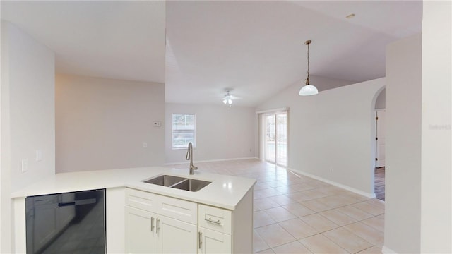 kitchen featuring a sink, black dishwasher, arched walkways, a peninsula, and light countertops