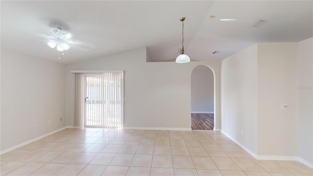 spare room with arched walkways, light tile patterned floors, a ceiling fan, and vaulted ceiling