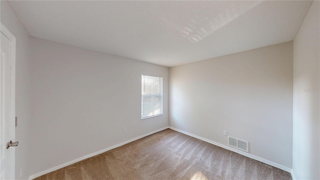 empty room with visible vents, baseboards, and carpet