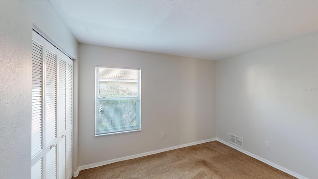 unfurnished bedroom featuring visible vents, carpet floors, and baseboards