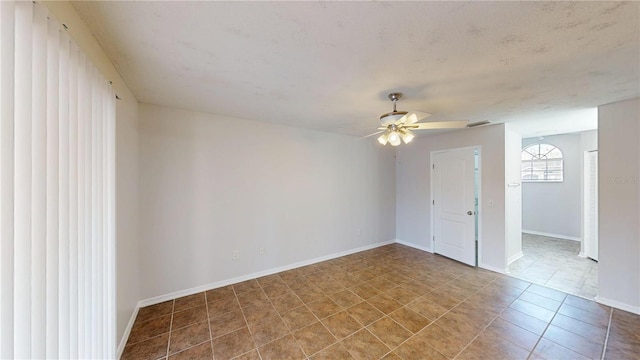 empty room featuring baseboards, a ceiling fan, and tile patterned flooring