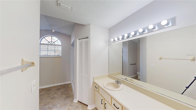bathroom featuring toilet, a textured ceiling, a closet, lofted ceiling, and vanity