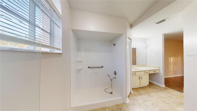 bathroom with visible vents, tile patterned flooring, baseboards, walk in shower, and vanity
