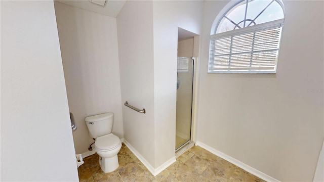 bathroom with baseboards, toilet, and a stall shower