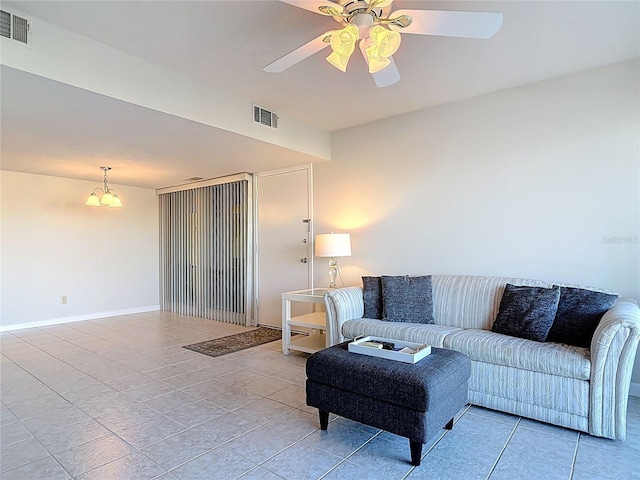 living room with light tile patterned floors, visible vents, ceiling fan with notable chandelier, and baseboards