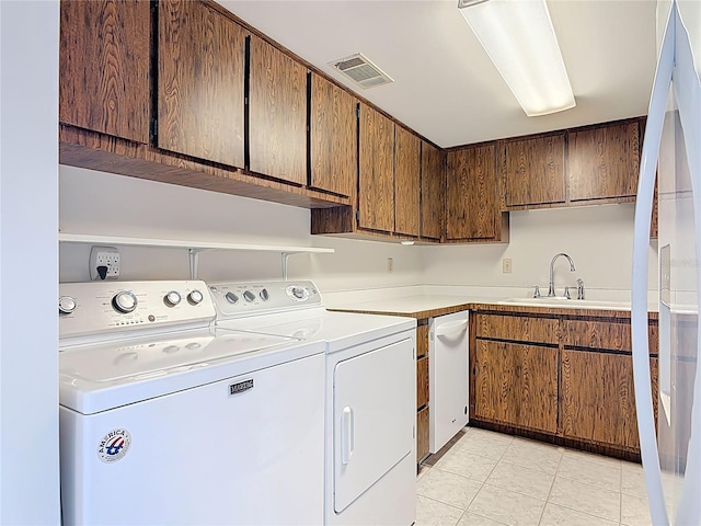 clothes washing area featuring light tile patterned floors, separate washer and dryer, visible vents, and a sink