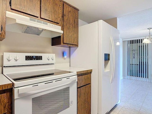 kitchen with brown cabinets, under cabinet range hood, white appliances, light tile patterned flooring, and light countertops