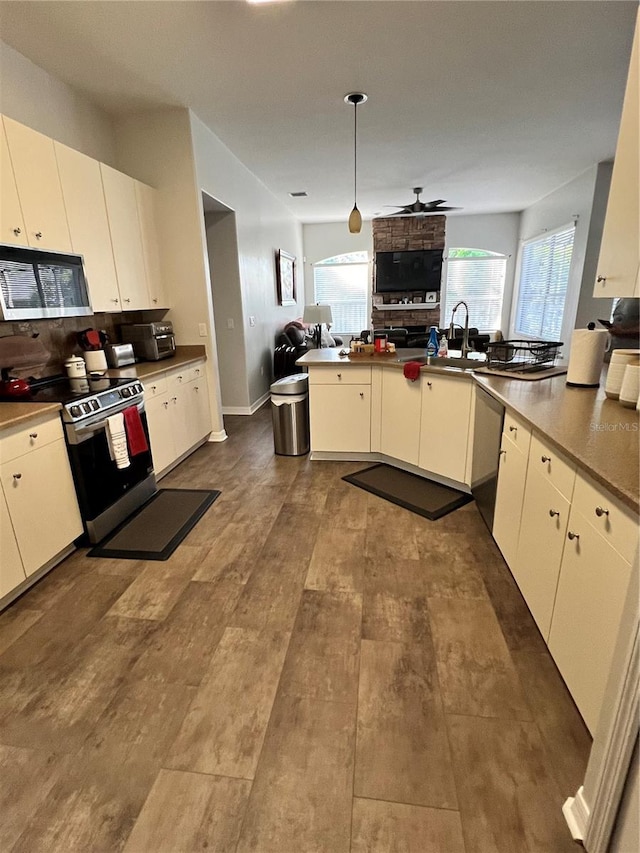 kitchen with decorative light fixtures, open floor plan, appliances with stainless steel finishes, a ceiling fan, and dark wood-style flooring