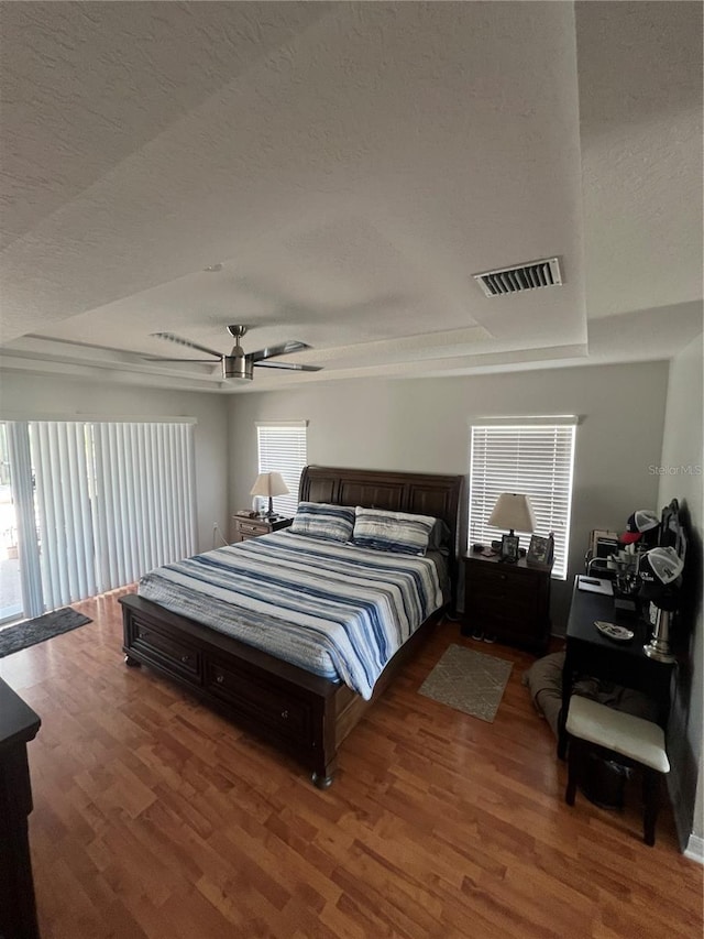 bedroom featuring visible vents, a textured ceiling, and wood finished floors