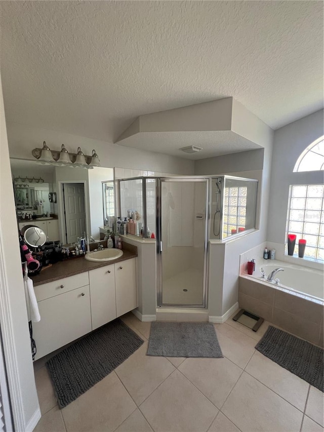 bathroom with a textured ceiling, a shower stall, tile patterned flooring, a bath, and vanity