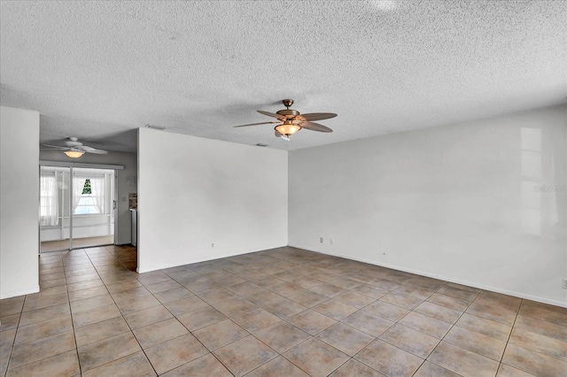 empty room with tile patterned floors, visible vents, a textured ceiling, and ceiling fan