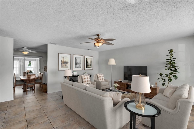 living room with a textured ceiling, light tile patterned flooring, visible vents, and ceiling fan