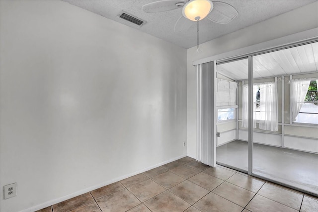 spare room with tile patterned floors, visible vents, a textured ceiling, and ceiling fan