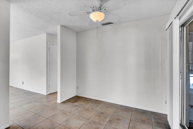 unfurnished room featuring light tile patterned floors, visible vents, a textured ceiling, and a ceiling fan