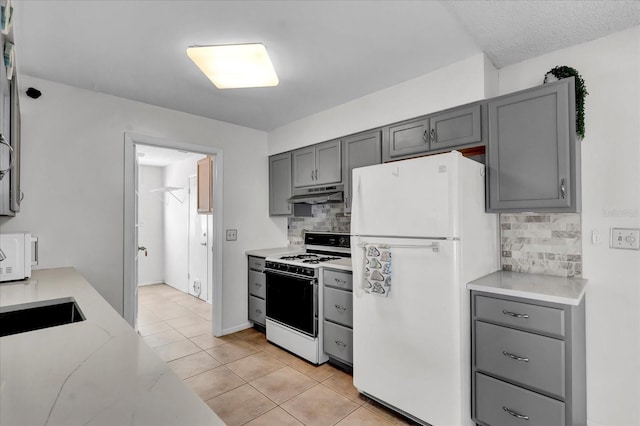 kitchen featuring under cabinet range hood, white appliances, gray cabinetry, and light countertops