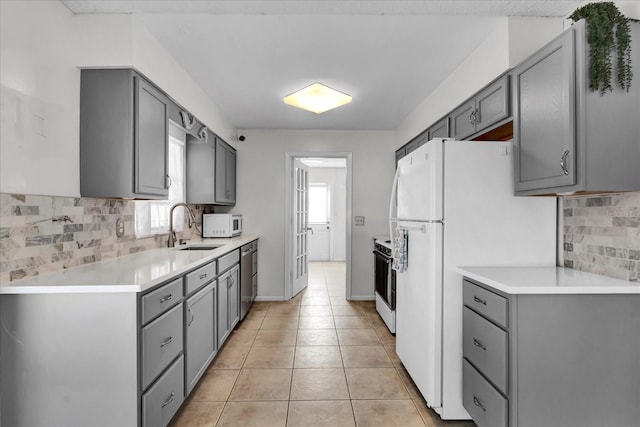 kitchen featuring a sink, white appliances, gray cabinets, and light tile patterned floors