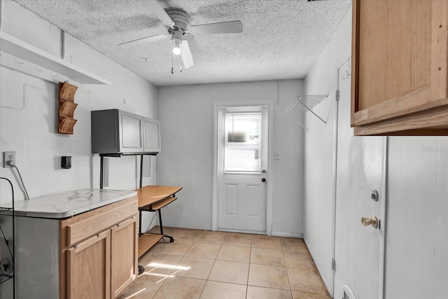 kitchen with light countertops, light tile patterned flooring, a ceiling fan, and a textured ceiling