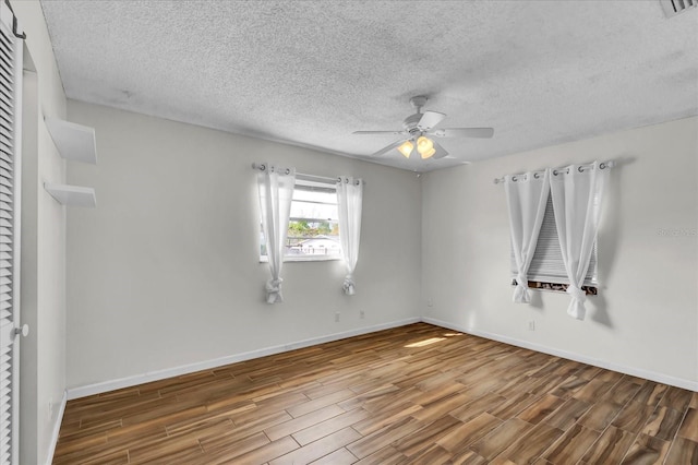 unfurnished room with a textured ceiling, wood finished floors, baseboards, and ceiling fan