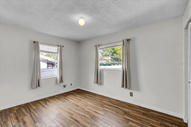 spare room featuring wood finished floors, baseboards, and a healthy amount of sunlight