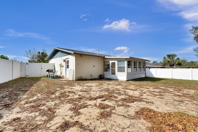 rear view of property with a sunroom, a fenced backyard, and a gate