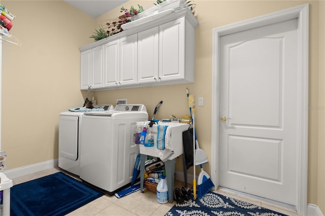 washroom with washing machine and clothes dryer, baseboards, light tile patterned floors, and cabinet space