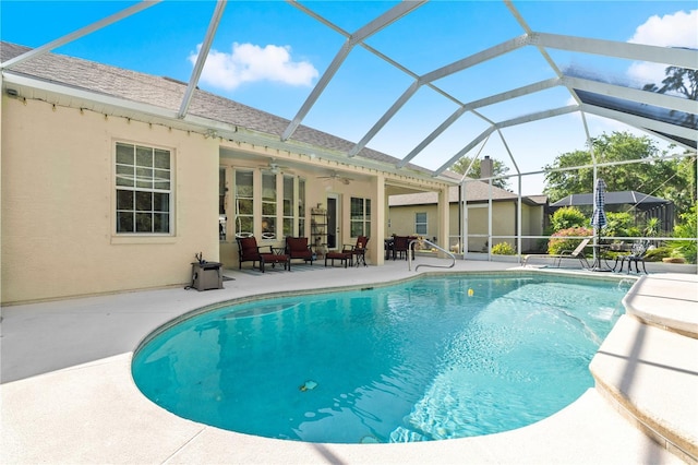 outdoor pool with glass enclosure, ceiling fan, and a patio area