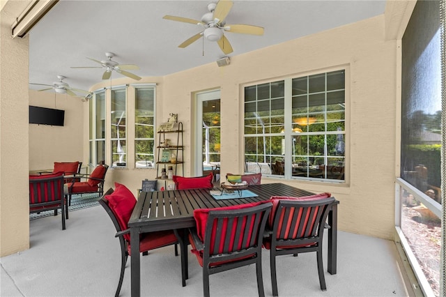 sunroom with a ceiling fan, carpet, and outdoor dining space