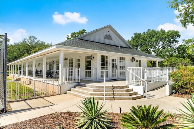 country-style home featuring a porch and roof with shingles