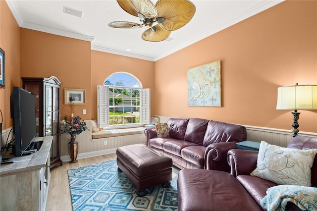 living area featuring wainscoting, ceiling fan, ornamental molding, and light wood finished floors