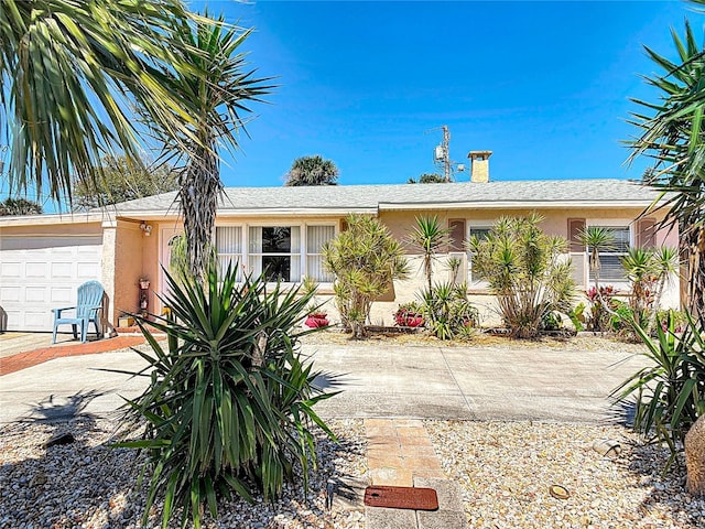 ranch-style house with stucco siding, an attached garage, a chimney, and concrete driveway