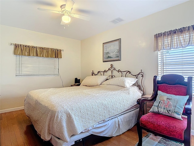 bedroom featuring hardwood / wood-style floors, a ceiling fan, visible vents, and baseboards