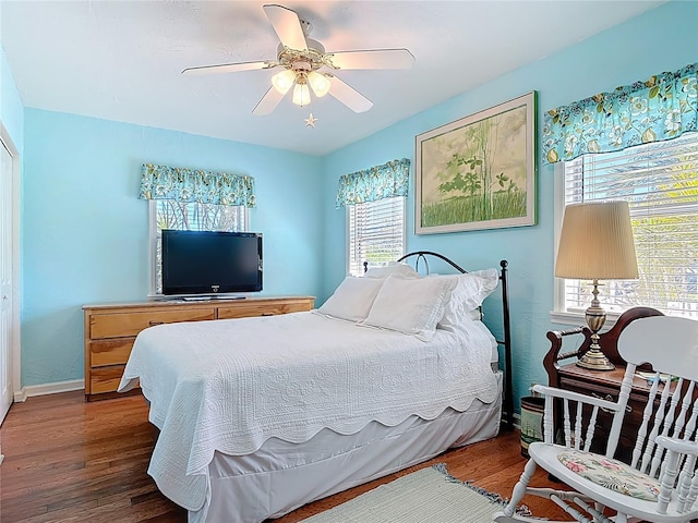 bedroom with ceiling fan, baseboards, multiple windows, and wood finished floors