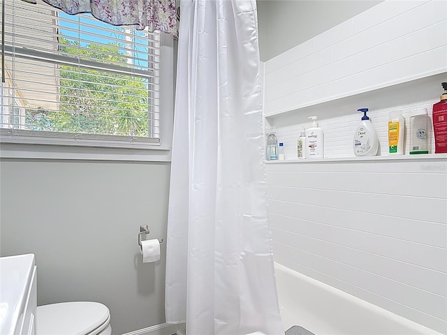 bathroom with toilet, baseboards, and shower / bath combo
