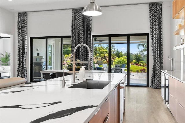 96 Del Palma Dr, Palm Coast, FL 32137 - kitchen featuring a wealth of natural light, a sink, light wood finished floors, light stone countertops, and brown cabinetry