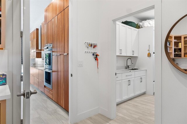 96 Del Palma Dr, Palm Coast, FL 32137 - kitchen with light countertops, stainless steel double oven, light wood-style flooring, a sink, and white cabinets