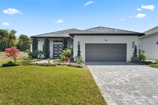 96 Del Palma Dr, Palm Coast, FL 32137 - prairie-style home with a garage, decorative driveway, stucco siding, and a front lawn