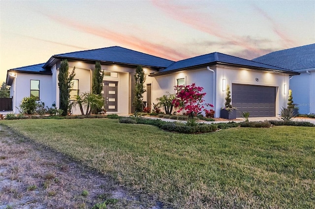 96 Del Palma Dr, Palm Coast, FL 32137 - prairie-style house with a lawn, stucco siding, and a garage