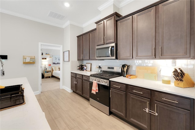 49 Narvarez Ave, Saint Augustine, FL 32084 - kitchen with stainless steel appliances, ornamental molding, dark brown cabinets, light countertops, and backsplash