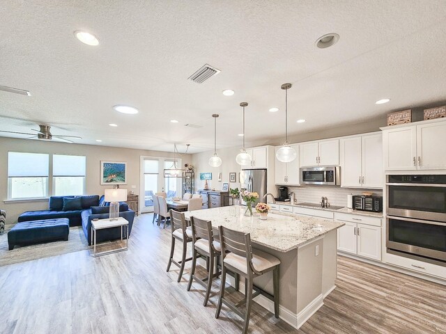 68 Los Lagos Blvd, Palm Coast, FL 32137 - kitchen featuring appliances with stainless steel finishes, light wood-type flooring, a breakfast bar, open floor plan, and a textured ceiling