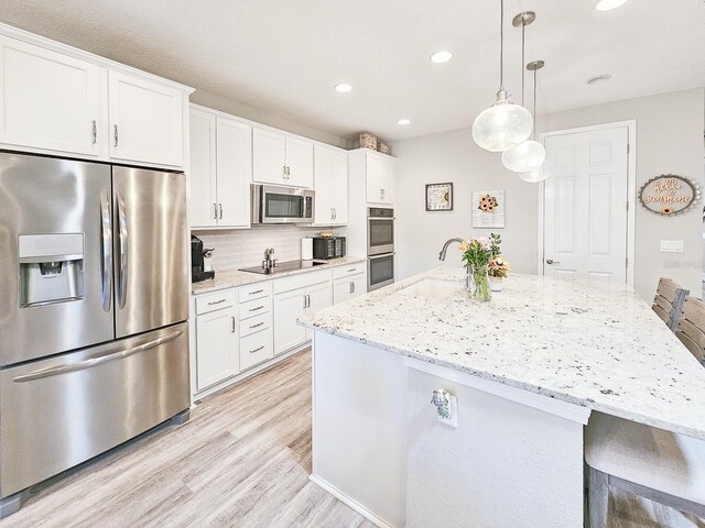 68 Los Lagos Blvd, Palm Coast, FL 32137 - kitchen with stainless steel appliances, a sink, light wood-style floors, an island with sink, and white cabinets