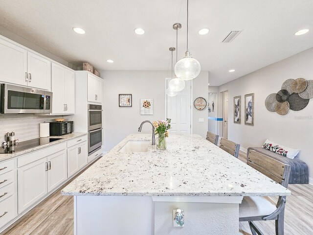 68 Los Lagos Blvd, Palm Coast, FL 32137 - kitchen with appliances with stainless steel finishes, a sink, light wood-style floors, a kitchen breakfast bar, and recessed lighting