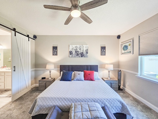 68 Los Lagos Blvd, Palm Coast, FL 32137 - carpeted bedroom featuring a barn door, connected bathroom, baseboards, ceiling fan, and a textured ceiling