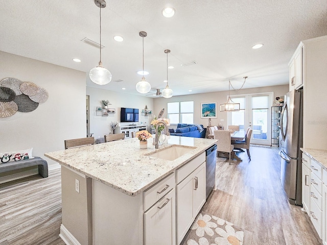 68 Los Lagos Blvd, Palm Coast, FL 32137 - kitchen featuring stainless steel appliances, a sink, open floor plan, light wood-style floors, and a center island with sink