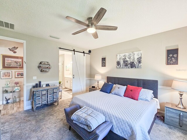 68 Los Lagos Blvd, Palm Coast, FL 32137 - carpeted bedroom with a barn door, a textured ceiling, ensuite bathroom, and ceiling fan